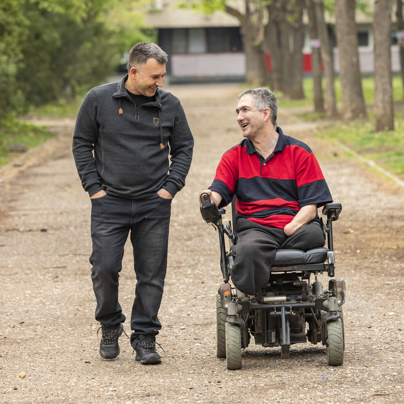 Disabled Person in Electric Wheelchair in a Public Park With a Friend